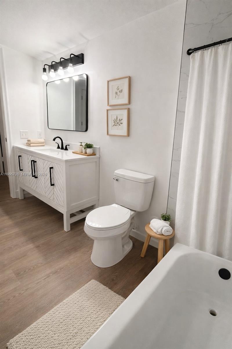 A modern bathroom features a white vanity, a toilet, and a bathtub with a shower — 460 S Park Rd # 110, Hollywood FL 33021, HOLLYWOOD, FL