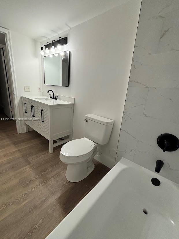 A bathroom features a white vanity, a toilet, and a bathtub with marble-look tile — 460 S Park Rd # 110, Hollywood FL 33021, HOLLYWOOD, FL