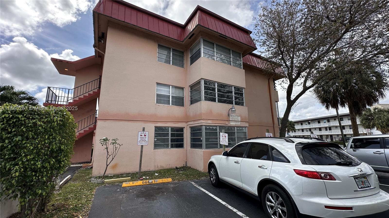 A three-story peach-colored apartment building with a red metal roof and exterior staircases — 19001 NE 14th Ave # 145, Miami FL 33179, MIAMI, FL