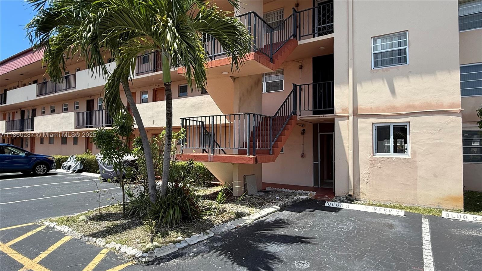 An exterior view of a multi-story apartment building with an outdoor staircase and parking lot — 19001 NE 14th Ave # 145, Miami FL 33179, MIAMI, FL