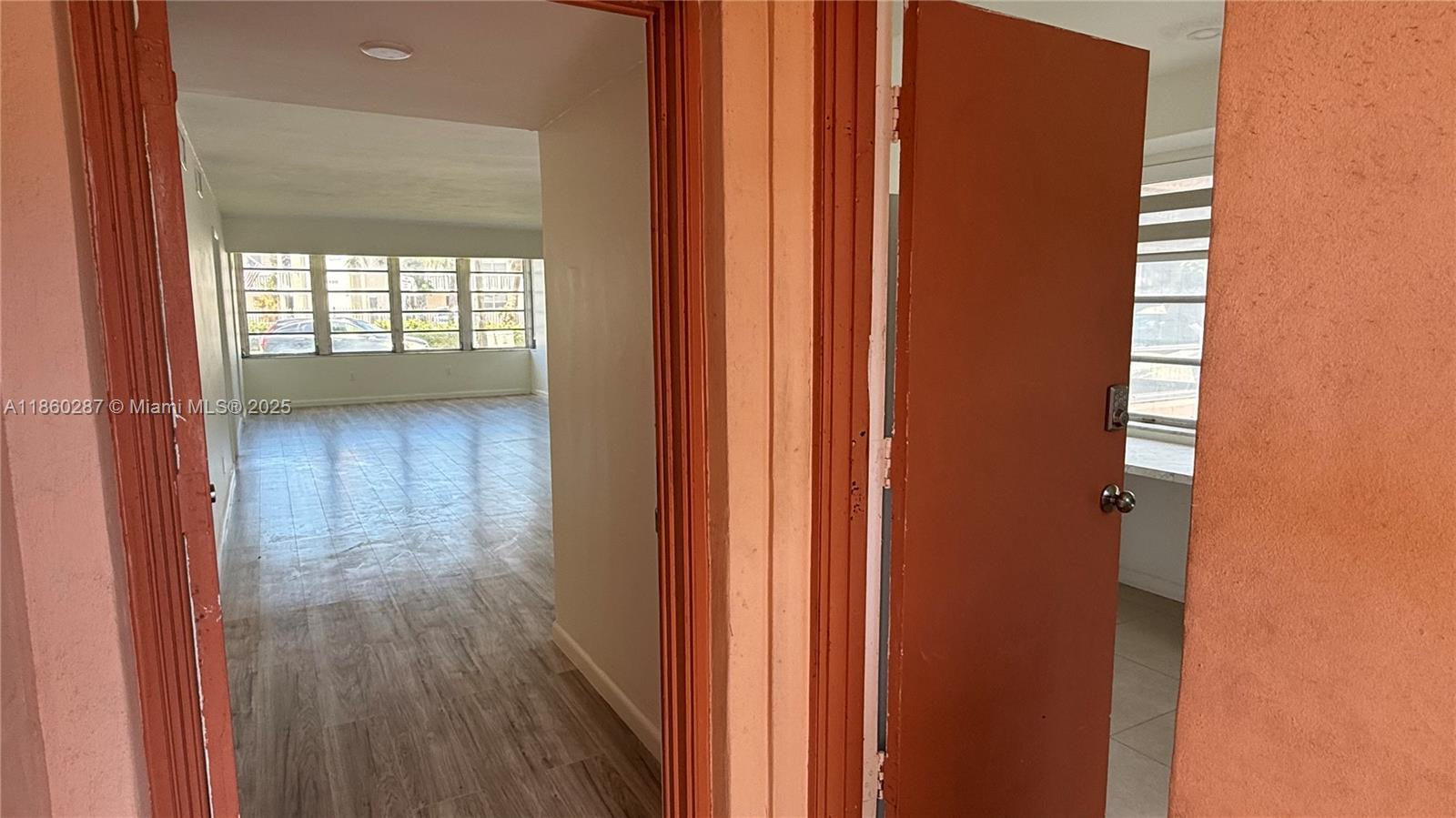 A view through two doorways shows a living area with wood-look flooring and large windows — 19001 NE 14th Ave # 145, Miami FL 33179, MIAMI, FL