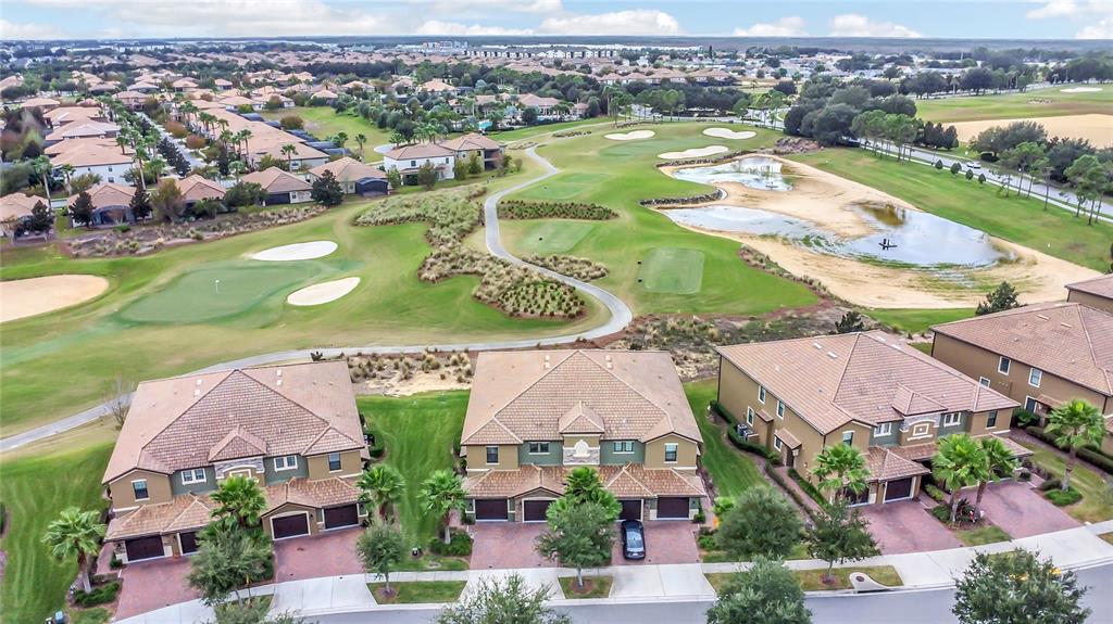 An aerial view shows three multi-story residential buildings situated along a golf course with ponds — 9038 AZALEA SANDS LANE UNIT 1, DAVENPORT, FL