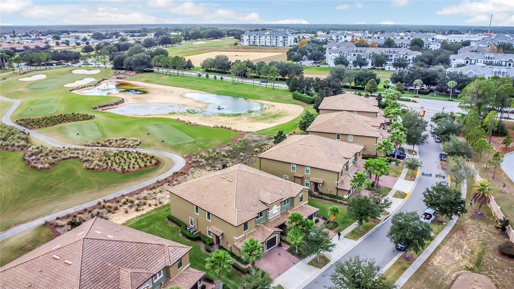 An aerial view shows multi-story residential buildings situated alongside a golf course and pond — 9038 AZALEA SANDS LANE UNIT 1, DAVENPORT, FL