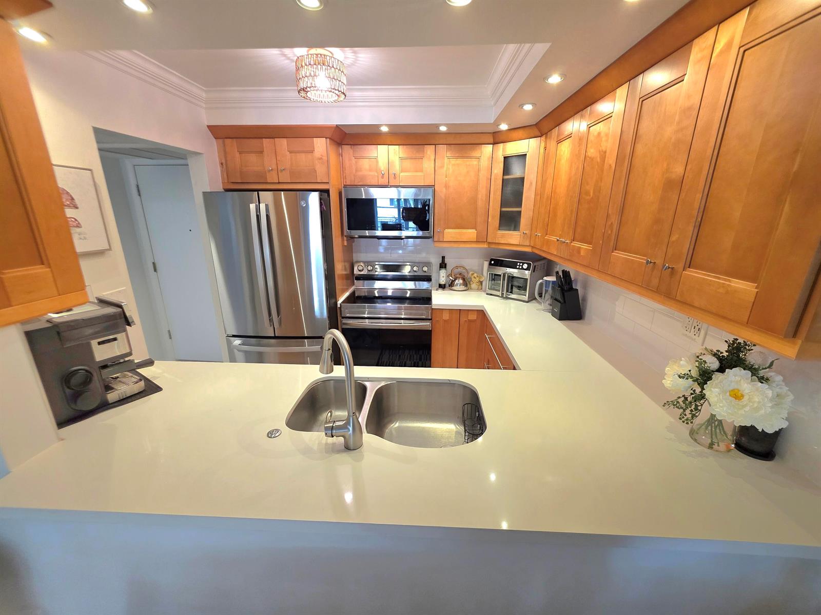 A kitchen features light wood cabinets, stainless steel appliances, and white countertops with a sink — 5680 SW 3rd Place # 206, Margate FL 33068, MARGATE, FL