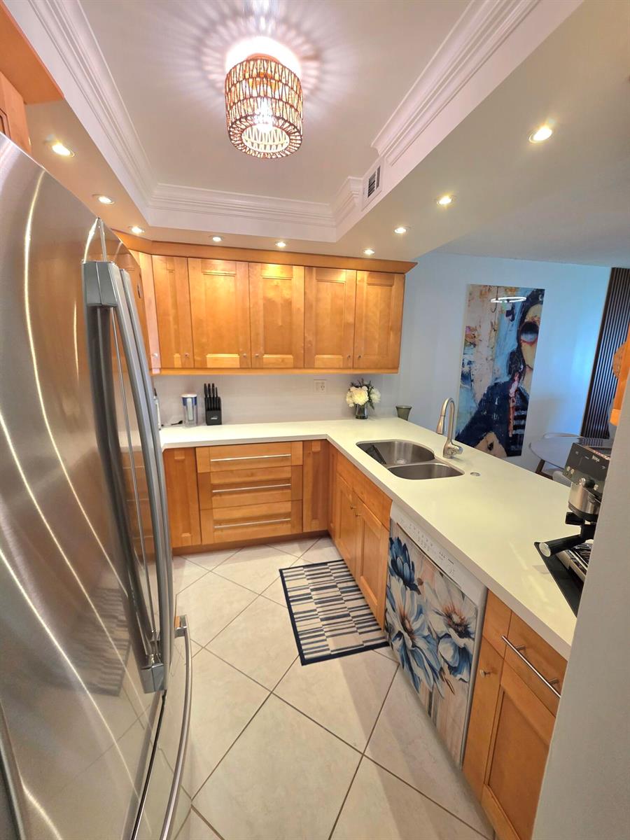 A kitchen with light wood cabinets, white countertops, stainless steel appliances, and tile flooring — 5680 SW 3rd Place # 206, Margate FL 33068, MARGATE, FL
