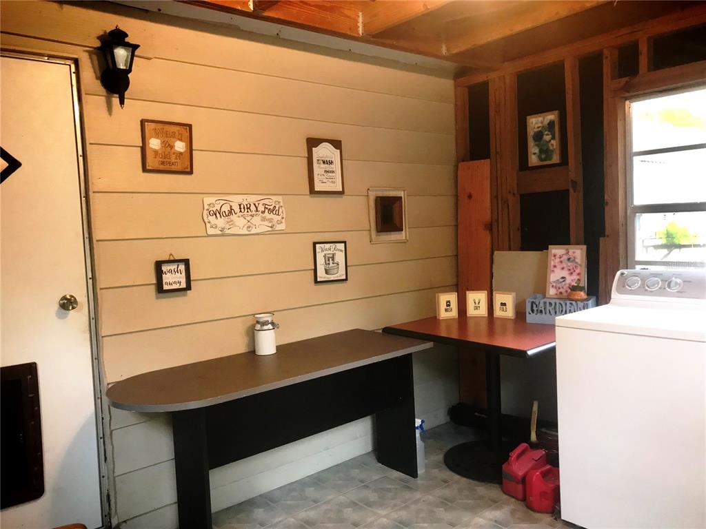 A laundry room features wood-paneled walls, a folding table, a small desk, and a washing machine — 118 MILLCREEK DRIVE, MELROSE, FL