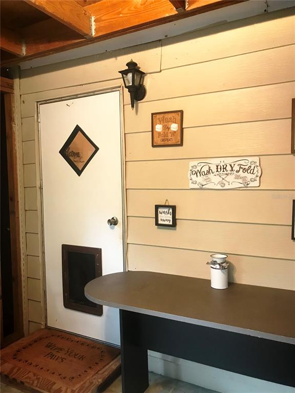 A laundry room with a pet door, a folding table, and wall-mounted laundry-themed signs — 118 MILLCREEK DRIVE, MELROSE, FL
