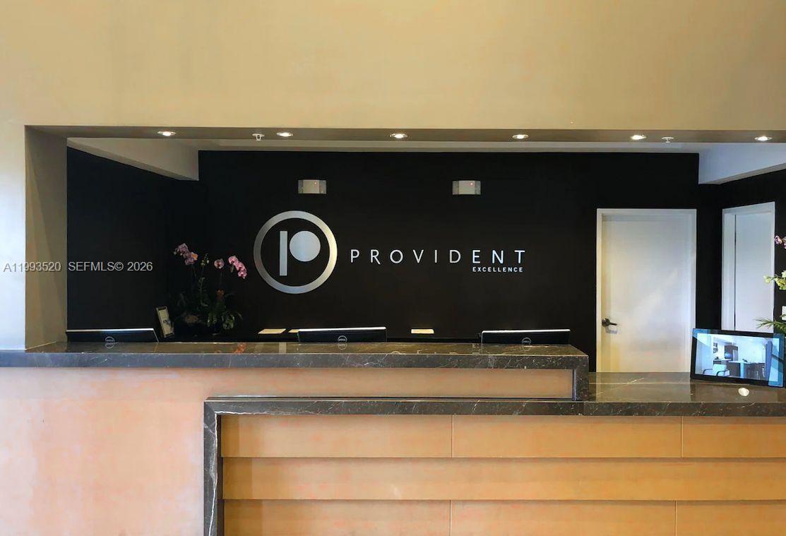 A reception desk with a dark stone countertop sits in front of a black wall — 5300 NW 87th Ave # 1107, Doral FL 33178, DORAL, FL