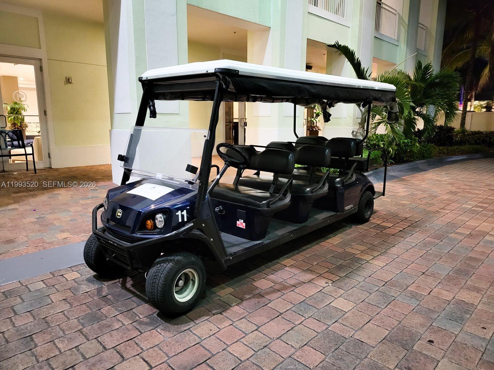 A dark blue multi-passenger golf cart is parked on a brick walkway outside a building — 5300 NW 87th Ave # 1107, Doral FL 33178, DORAL, FL