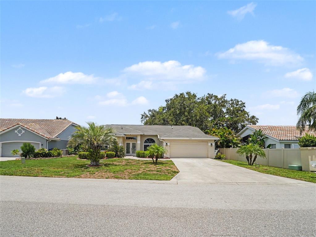 A single-story suburban house with a beige exterior, a two-car garage, and a paved driveway — 5325 GARDENS DR, SARASOTA, FL