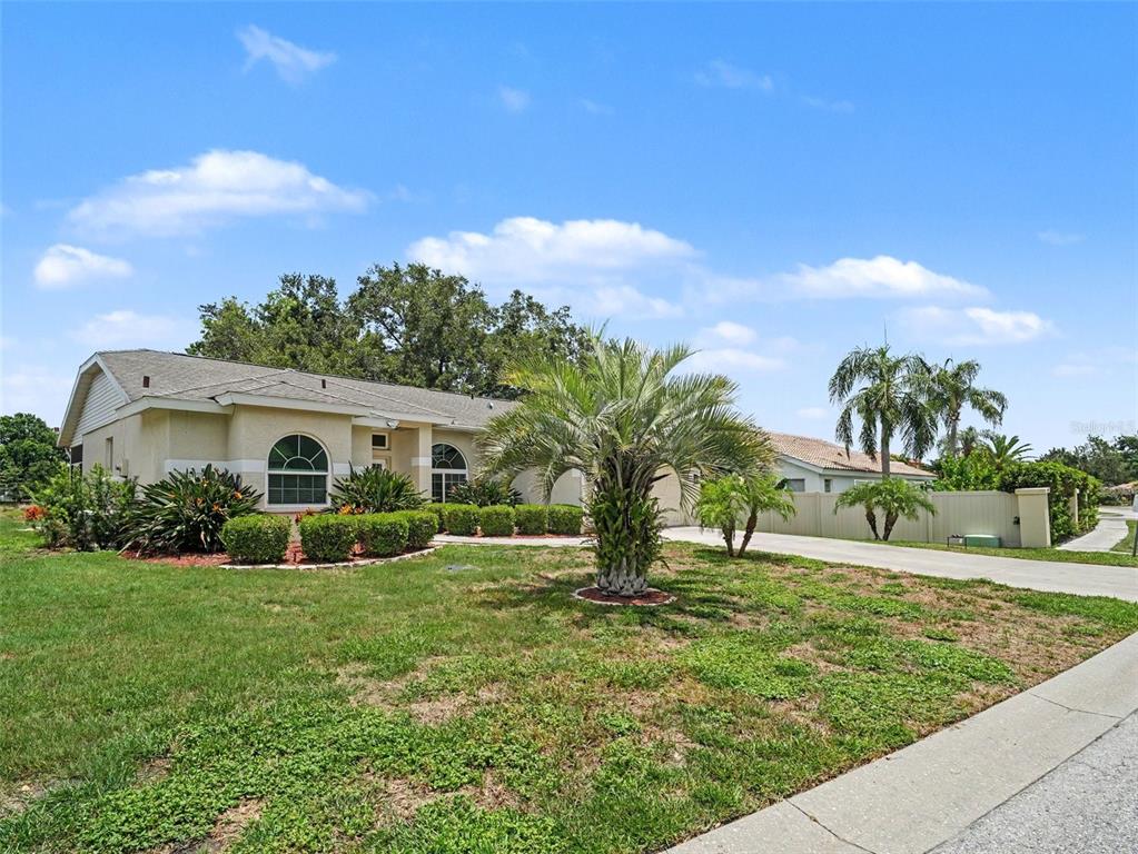 A single-story house with a beige stucco exterior, arched windows, and a palm tree lawn — 5325 GARDENS DR, SARASOTA, FL