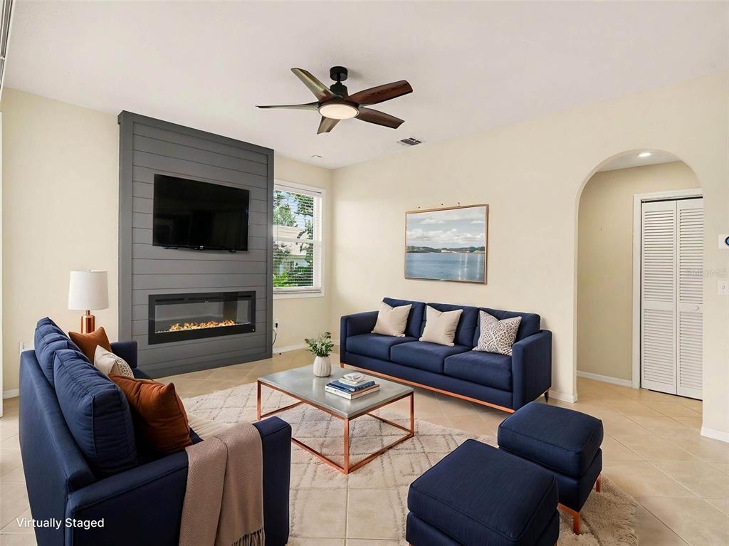 A living room features a gray shiplap fireplace wall, blue sofas, and a ceiling fan — 5325 GARDENS DR, SARASOTA, FL