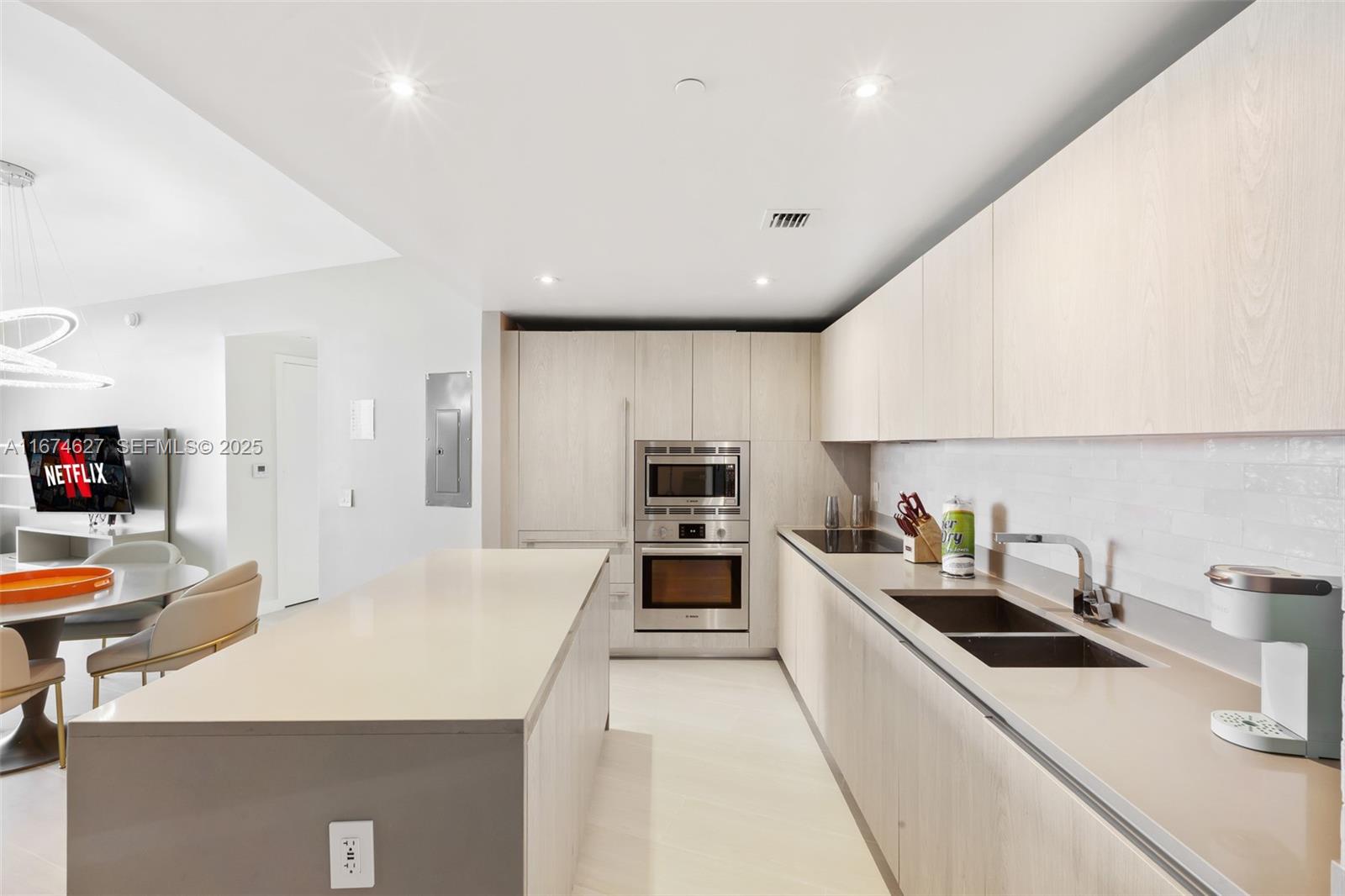 A modern kitchen features light wood cabinetry, a large quartz island, and stainless steel appliances — 4111 S Ocean Dr # 3108, Hollywood FL 33019, HOLLYWOOD, FL