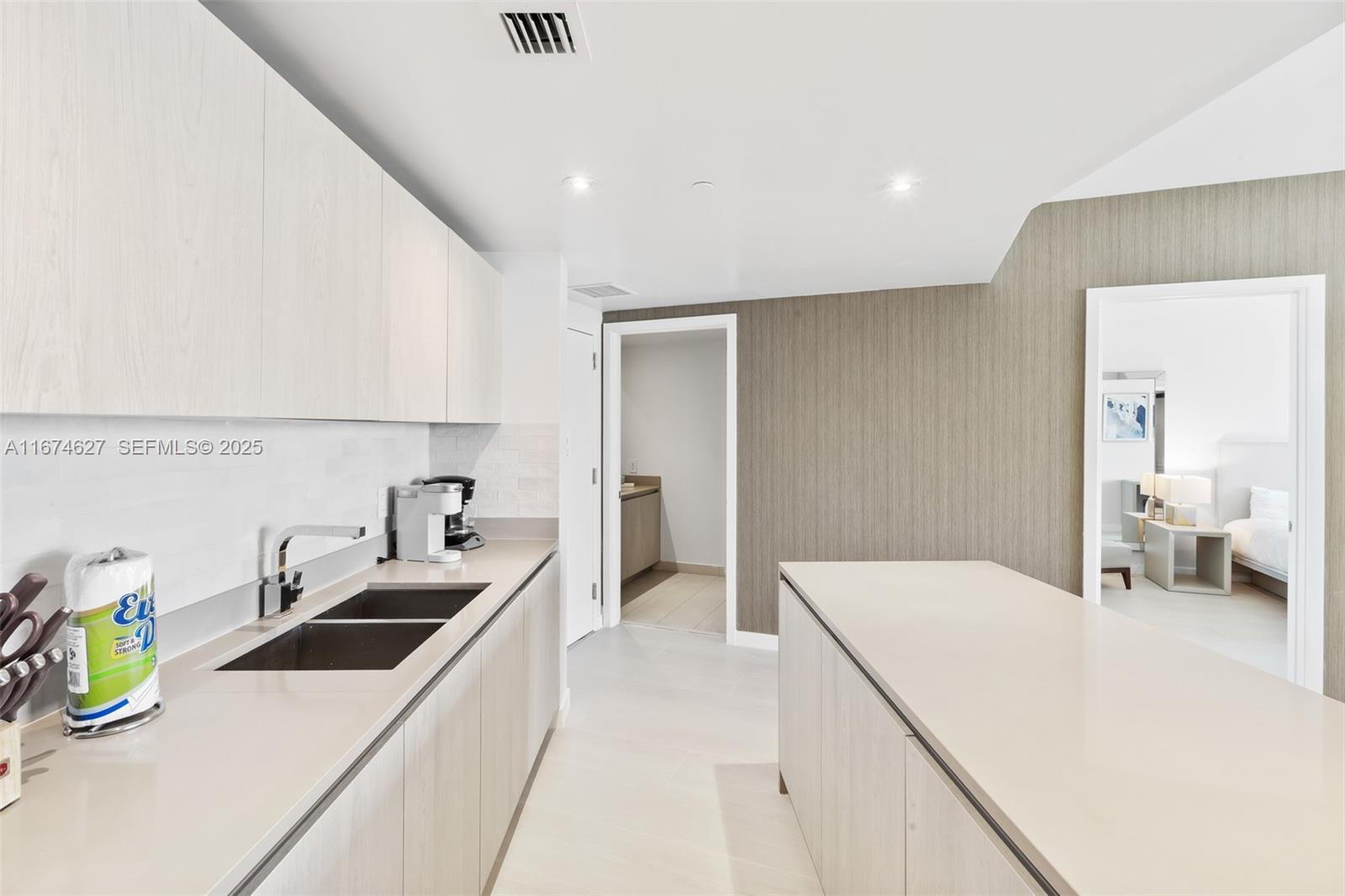 A modern kitchen features light wood cabinetry, a quartz island, and a double sink — 4111 S Ocean Dr # 3108, Hollywood FL 33019, HOLLYWOOD, FL