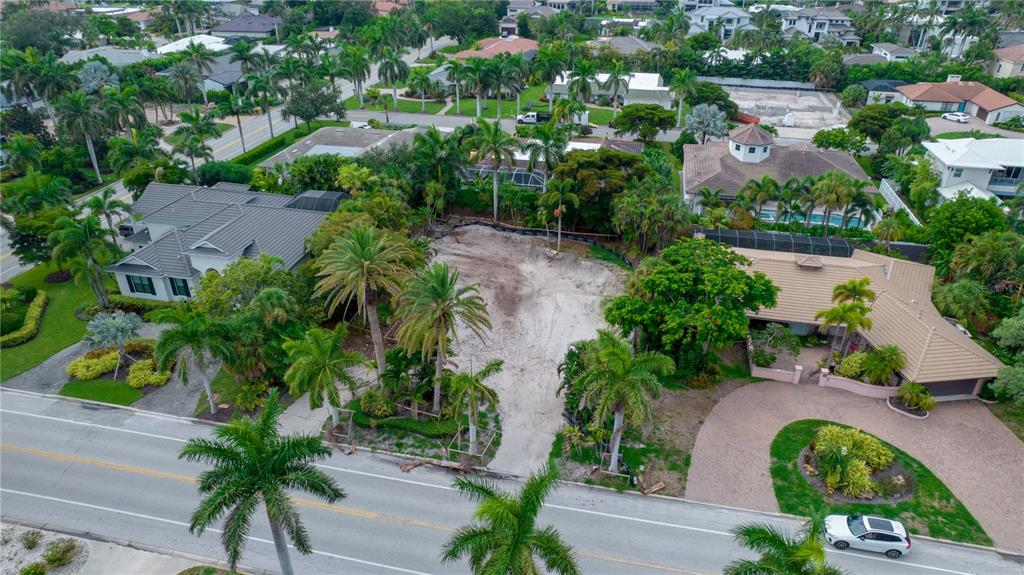 An aerial view shows a vacant, sandy residential lot situated between two houses and palm trees — 338 BIRD KEY DRIVE, SARASOTA, FL