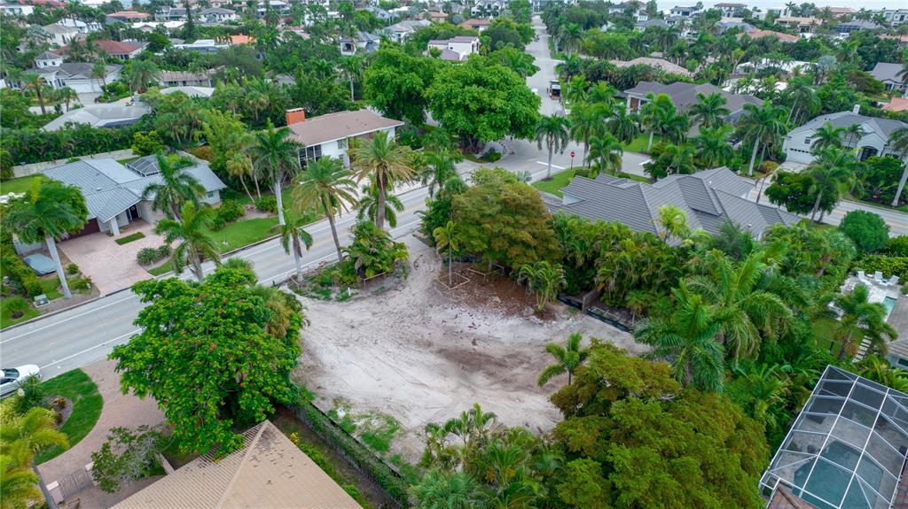 An aerial view shows a vacant, sandy residential lot surrounded by lush tropical landscaping and houses — 338 BIRD KEY DRIVE, SARASOTA, FL