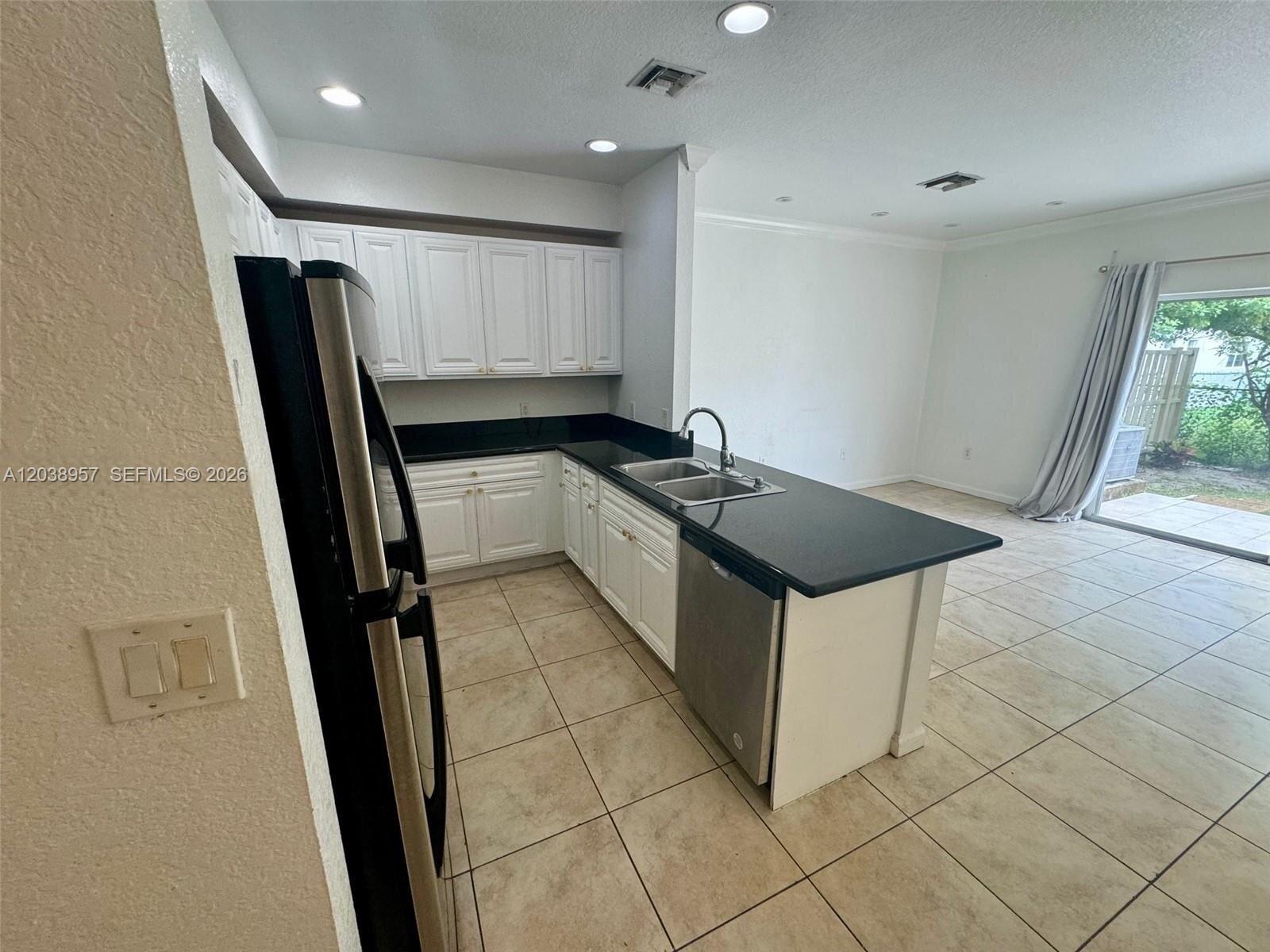 A kitchen features white cabinets, black countertops, stainless steel appliances, and tile flooring — 35 SE 3rd Ave # 11, Hallandale Beach FL 33009, HALLANDALE BEACH, FL