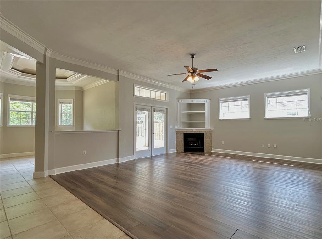 A living room with wood-look flooring, a corner fireplace, built-in shelving, and glass patio doors — 14424 NW 22ND PLACE, NEWBERRY, FL