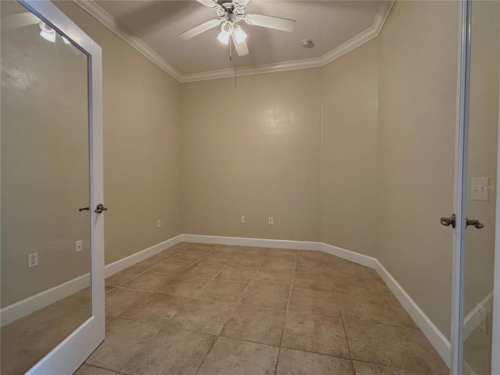 An empty room with beige walls, tile flooring, a ceiling fan, and double glass doors — 14424 NW 22ND PLACE, NEWBERRY, FL