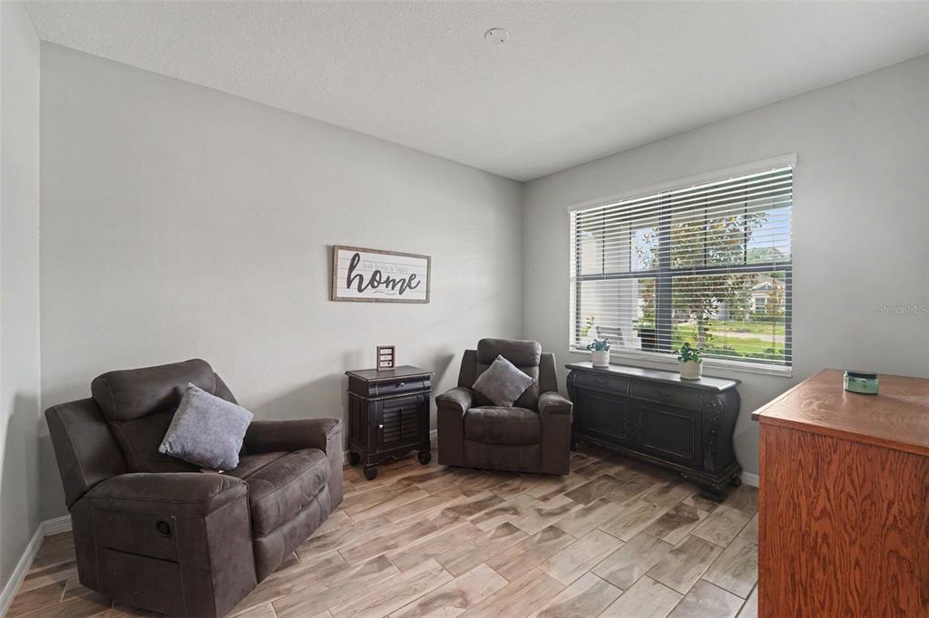 A living room features two brown recliners, a side table, and wood-look tile flooring — 13968 NESBIT COURT, HUDSON, FL