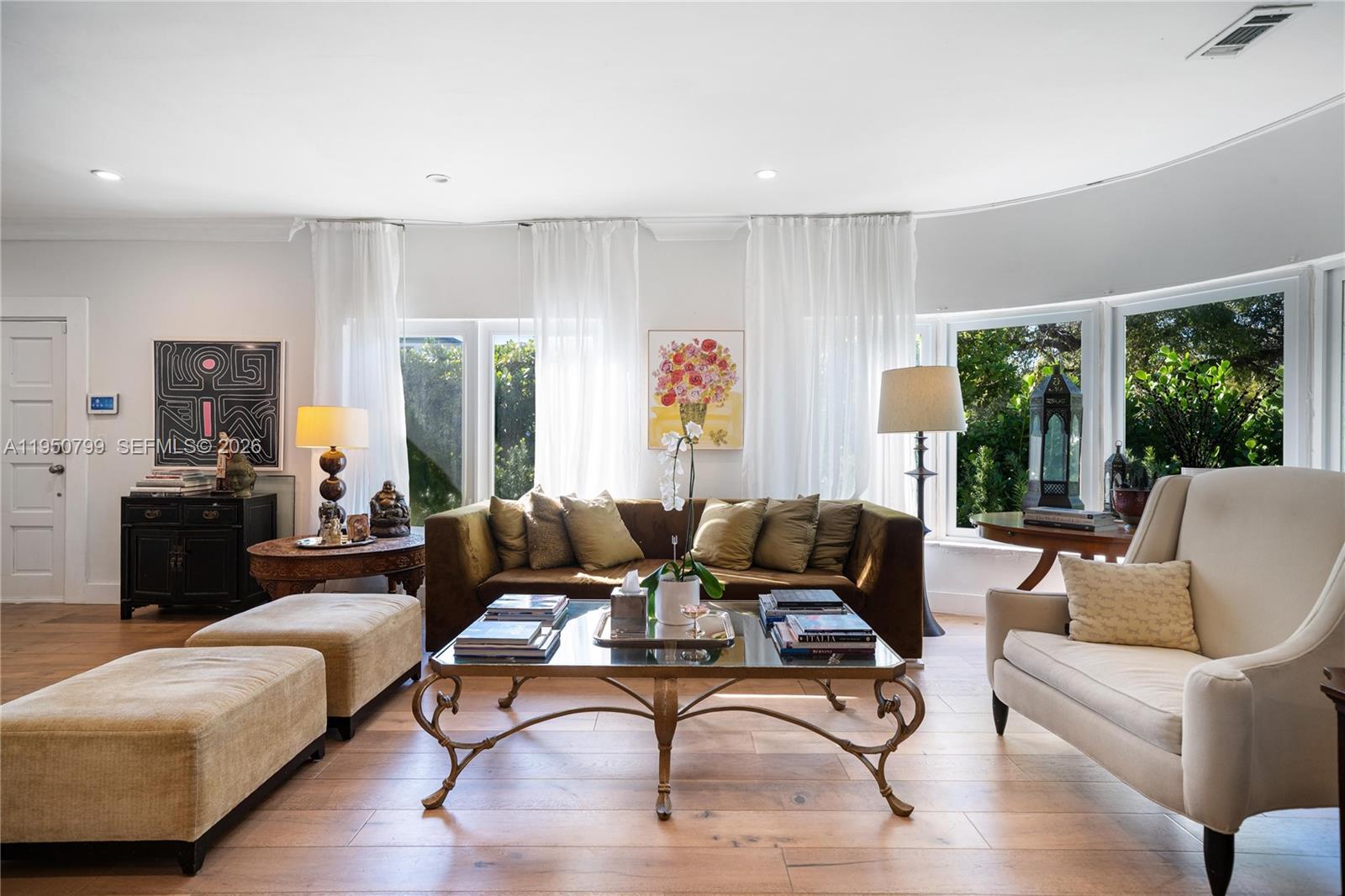 A living room features a brown sofa, a glass coffee table, and large windows — 463 W 62nd St, Miami Beach FL 33140, MIAMI BEACH, FL