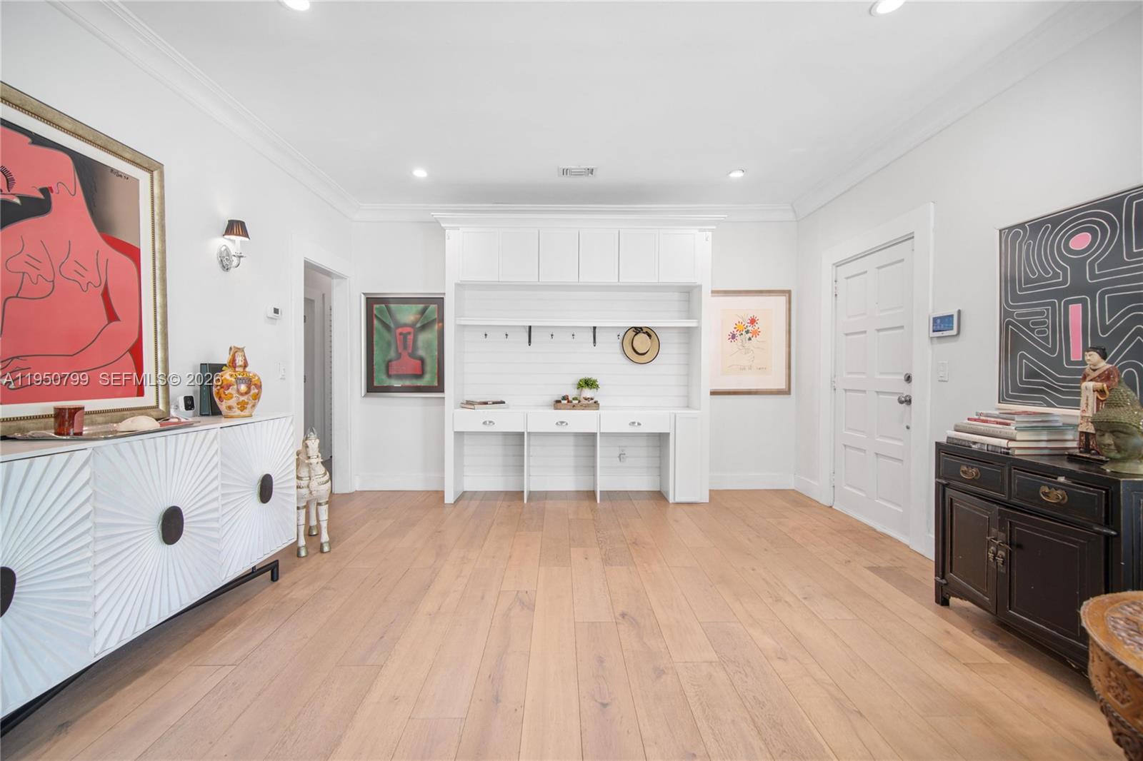A bright room features light wood floors, a white built-in desk unit, and eclectic artwork — 463 W 62nd St, Miami Beach FL 33140, MIAMI BEACH, FL