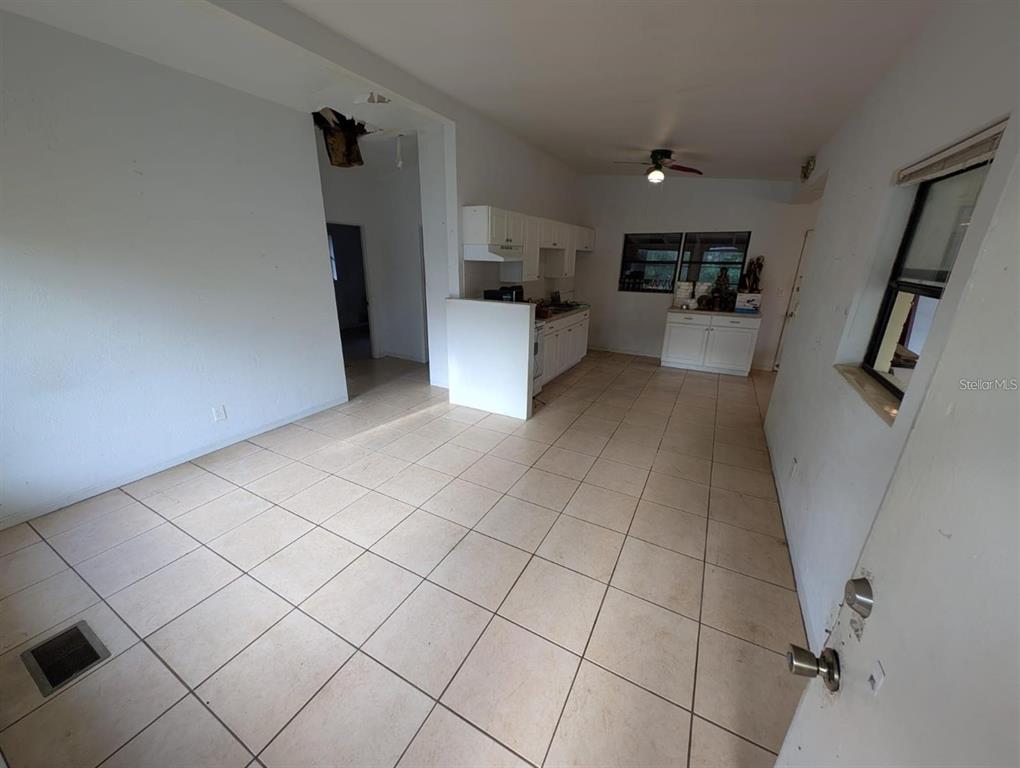 An interior view shows a tiled kitchen and dining area with white cabinets and walls — 765 GREENWAY PLACE, DAYTONA BEACH, FL
