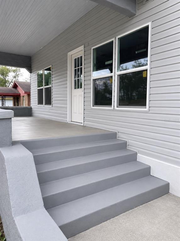 A gray house exterior features a covered porch, concrete steps, and white-framed windows and door — 2859 ORANGE STREET, MARIANNA, FL