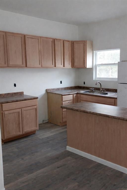 A kitchen features light wood cabinets, dark laminate countertops, and gray wood-look flooring — 2859 ORANGE STREET, MARIANNA, FL