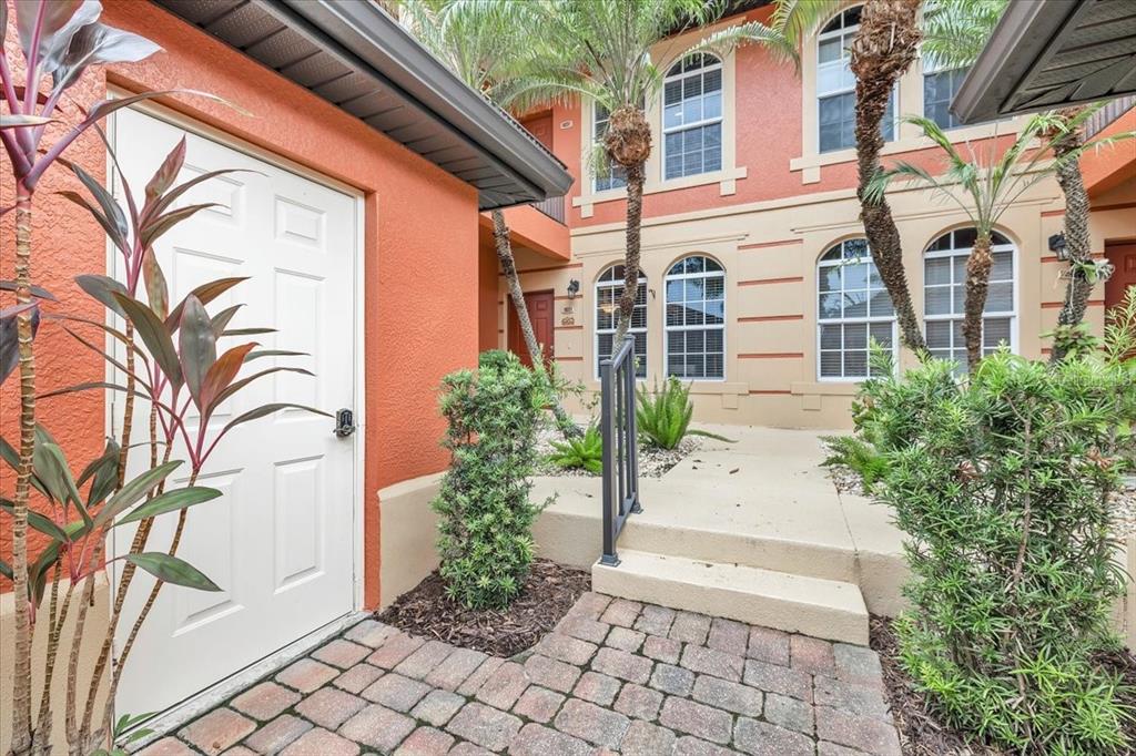 An exterior view of a building entrance with a white door, stairs, and palm trees — 3500 MONDOVI COURT UNIT 811, PUNTA GORDA, FL