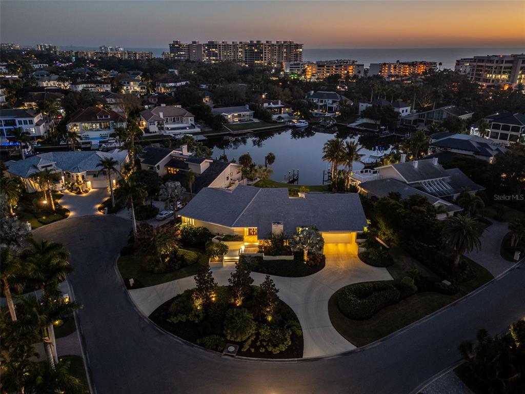 An aerial view of a waterfront house with a circular driveway at twilight — 1571 HARBOR CAY LANE, LONGBOAT KEY, FL