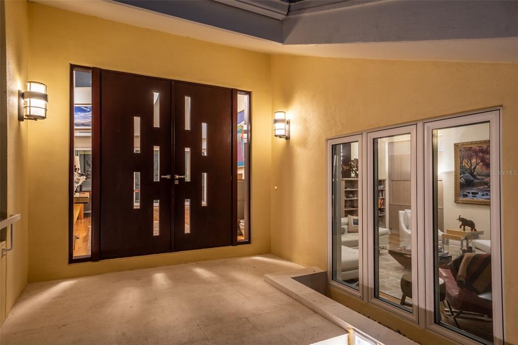 An entryway features double dark wood doors with glass inserts and large windows on yellow walls — 1571 HARBOR CAY LANE, LONGBOAT KEY, FL