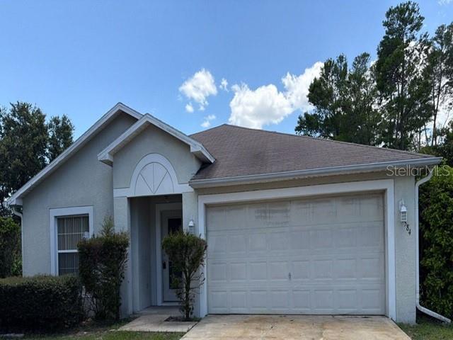 A single-story house with a beige stucco exterior and a two-car garage — 1584 FUJI DRIVE, TITUSVILLE, FL