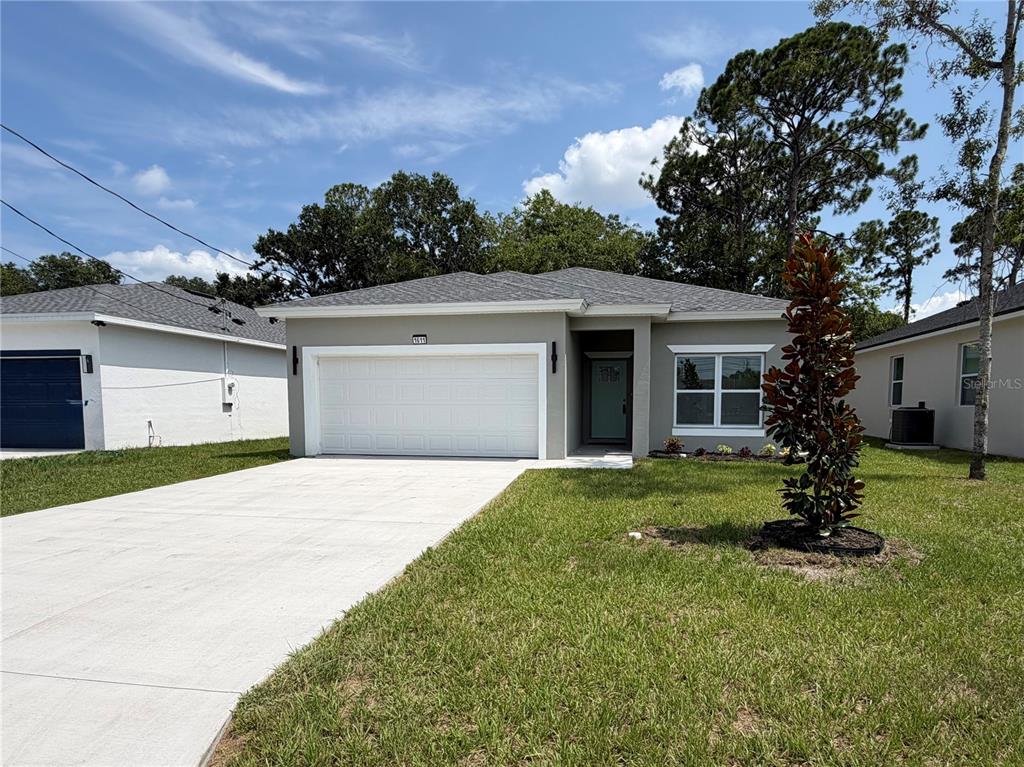 A single-story house with a white garage door, gray exterior, and a concrete driveway — 1611 ILLINOIS STREET, DAYTONA BEACH, FL