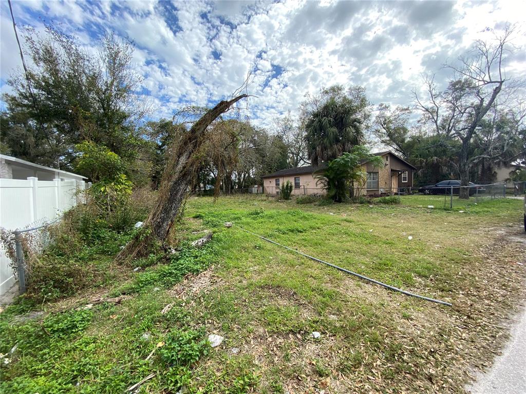 A vacant, grassy lot with a large dead tree trunk and a neighboring house — 2907 CORD STREET, TAMPA, FL