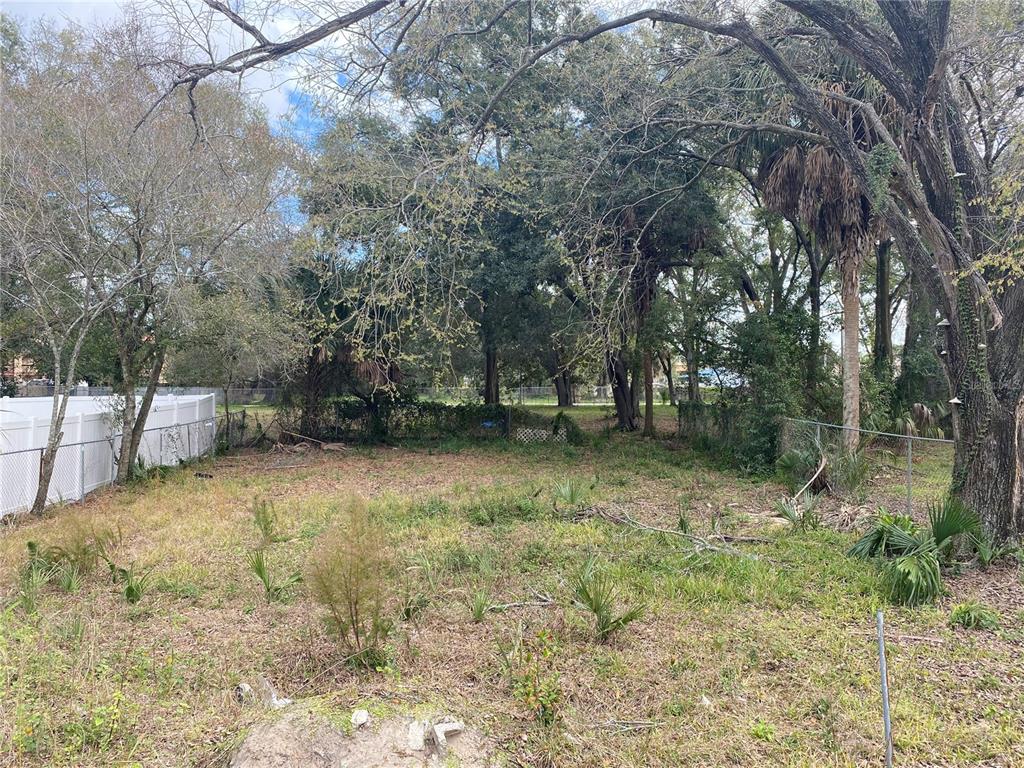 A vacant, grassy lot is enclosed by a white vinyl fence and mature trees — 2907 CORD STREET, TAMPA, FL