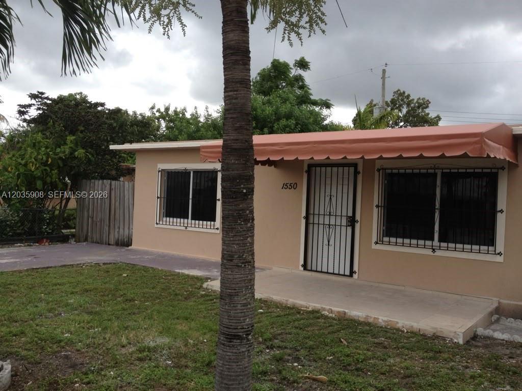 A single-story house with a tan exterior, a front porch, and a metal security door — 1550 E 10th Ave, Hialeah FL 33010, HIALEAH, FL