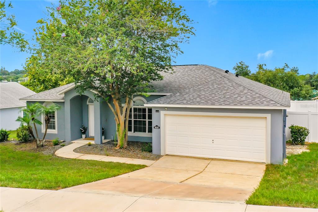 A single-story gray house with a two-car garage and a large tree in front — 1364 HILLVIEW DRIVE, CLERMONT, FL
