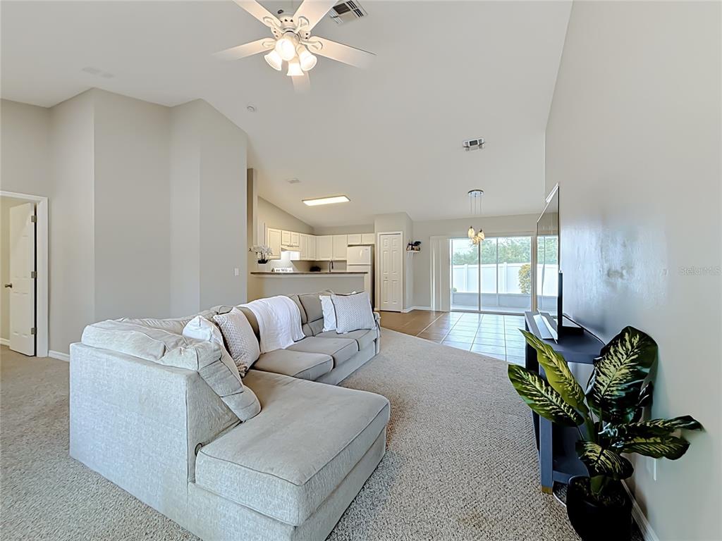 A living room with a sectional sofa, carpeted flooring, and an open kitchen in back — 1364 HILLVIEW DRIVE, CLERMONT, FL