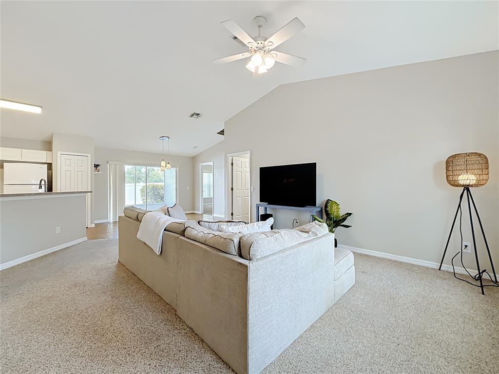 A living room features a beige sectional sofa, a television on a stand, and carpeted flooring — 1364 HILLVIEW DRIVE, CLERMONT, FL