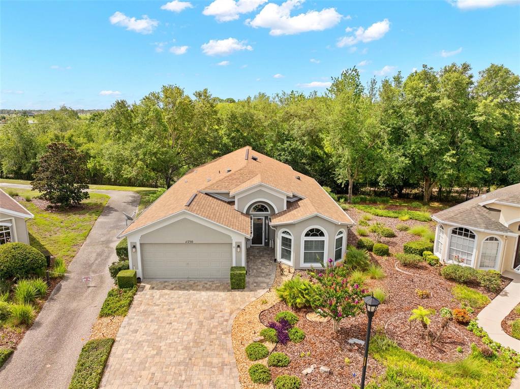 An aerial view shows a single-story house with a tan roof, garage, and paved driveway — 11750 TEAPOT COURT, SPRING HILL, FL