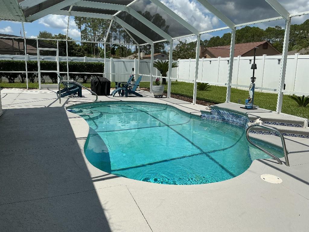 A screened-in backyard features a swimming pool with a tiled edge and concrete patio — 9 BARKLEY LANE, PALM COAST, FL