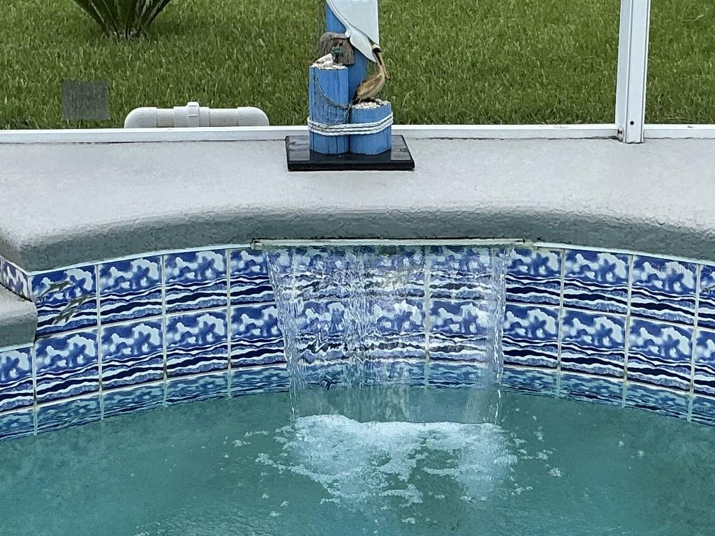 A pool water feature with a decorative pelican statue sits on a tiled pool wall — 9 BARKLEY LANE, PALM COAST, FL