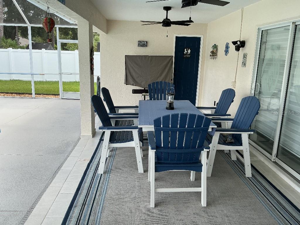 A covered patio features a blue dining set on a rug near a sliding door — 9 BARKLEY LANE, PALM COAST, FL