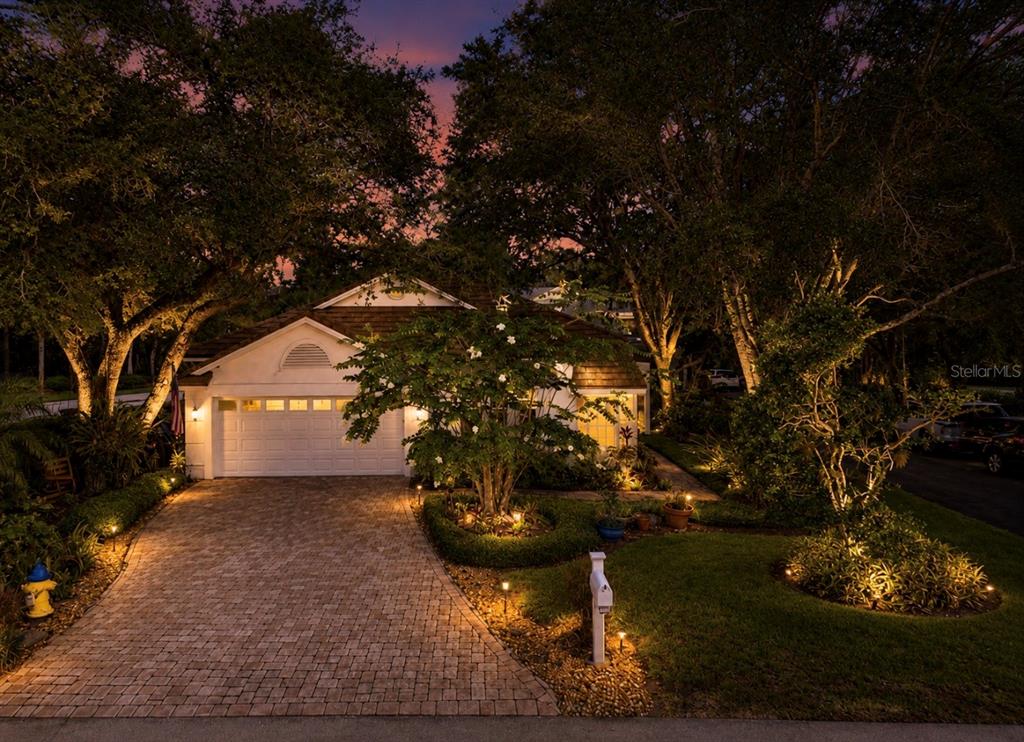 A single-story house with a paved driveway and landscape lighting at dusk — 5204 GREEN FOREST COURT, TAMPA, FL