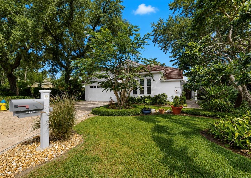 A white single-story house with a tiled roof sits behind a green lawn and trees — 5204 GREEN FOREST COURT, TAMPA, FL