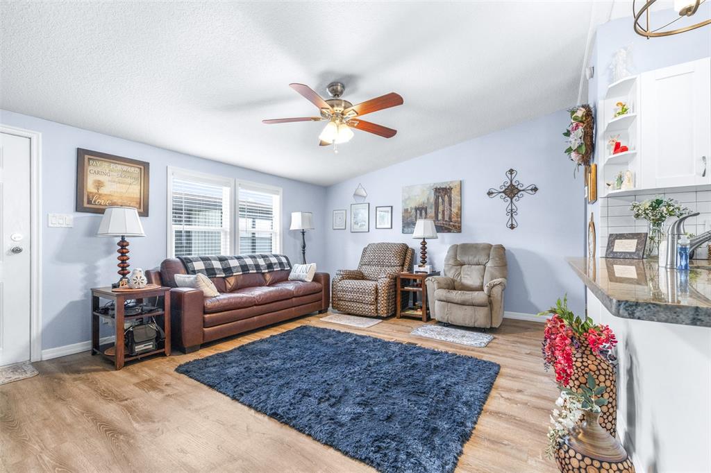 A living room features a brown leather sofa, two recliners, and a blue area rug — 3041 SHORT LEAF STREET, WESLEY CHAPEL, FL