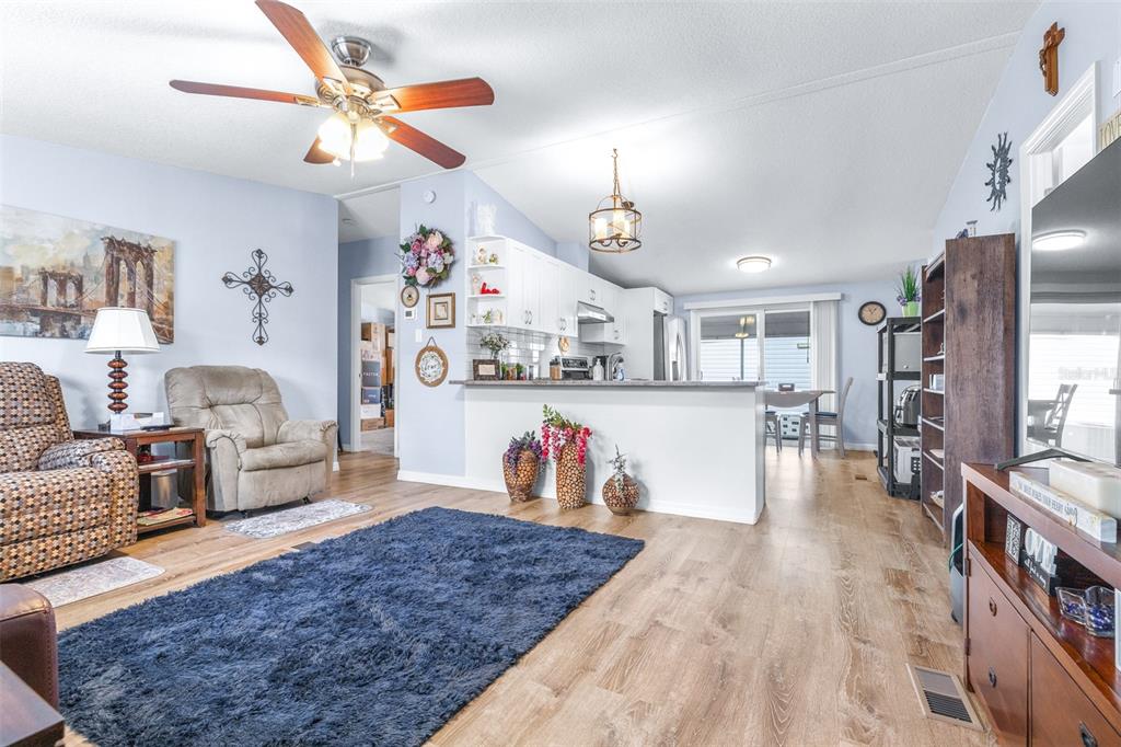 An open-concept living room and kitchen featuring wood-look flooring and a dark blue rug — 3041 SHORT LEAF STREET, WESLEY CHAPEL, FL