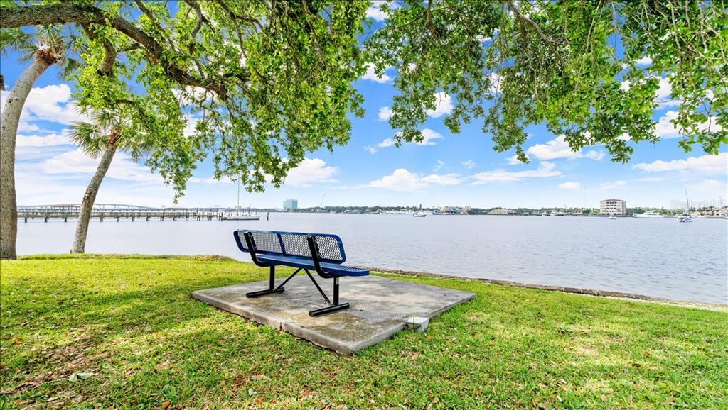 A blue metal bench sits on a concrete pad overlooking a wide waterfront view — 411 N HALIFAX AVENUE UNIT 304, DAYTONA BEACH, FL