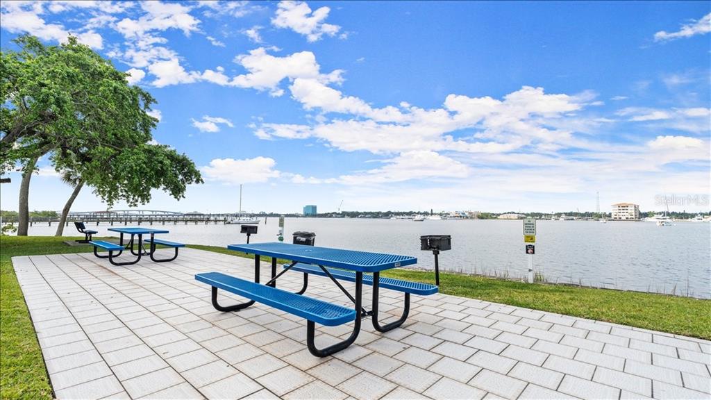 A waterfront park area features blue metal picnic tables on a paved patio — 411 N HALIFAX AVENUE UNIT 304, DAYTONA BEACH, FL